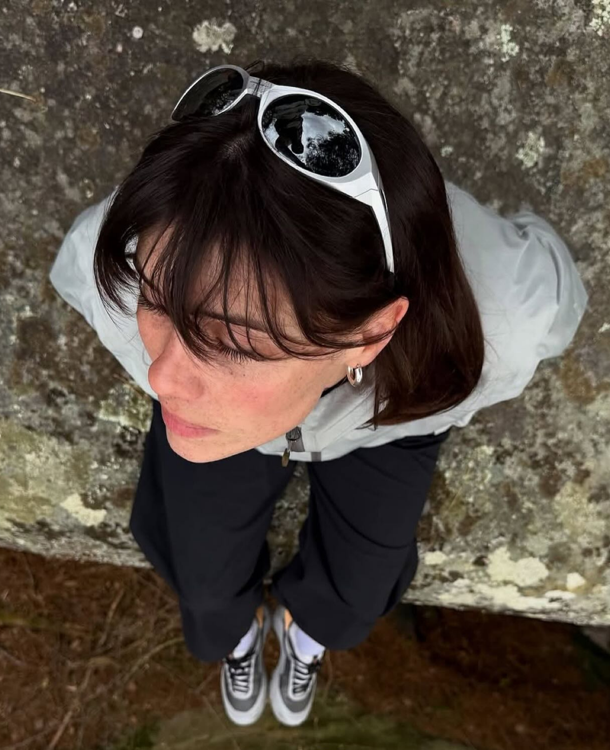 Silver sunglasses resting on the head in an outdoor streetwear look